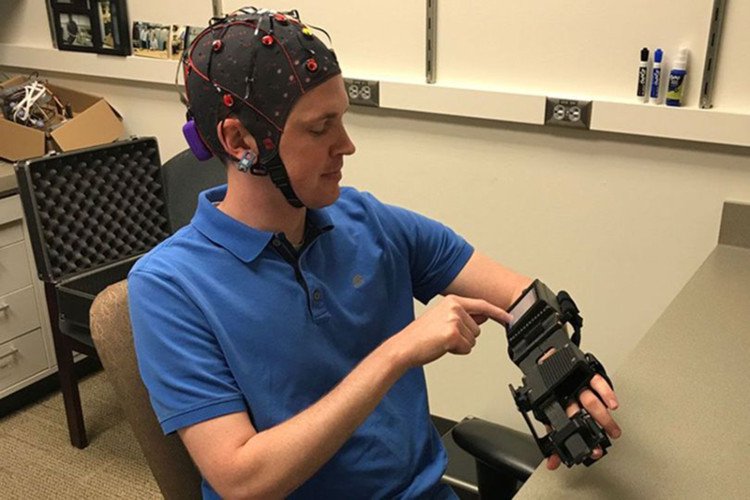 Bác sĩ Jarod Roland thử thiết bị làm cho bàn tay của mình mở và đóng theo đáp ứng các tín hiệu não